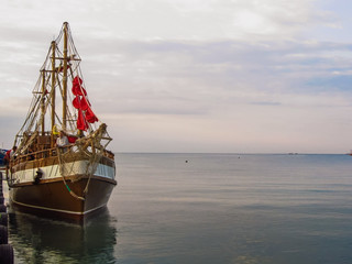 Fototapeta na wymiar ship with red sails into the sea at dawn