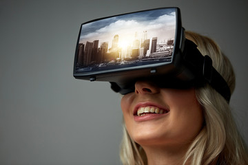 technology, augmented reality, entertainment and people concept - happy young woman with virtual headset or 3d glasses playing video game with singapore city on screen over gray background