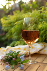 Trendy orange wine served on outdoor terrace in garden with flowers