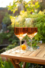 Trendy orange wine served on outdoor terrace in garden with flowers