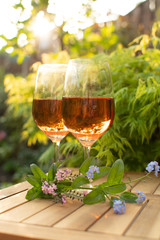 Trendy orange wine served on outdoor terrace in garden with flowers