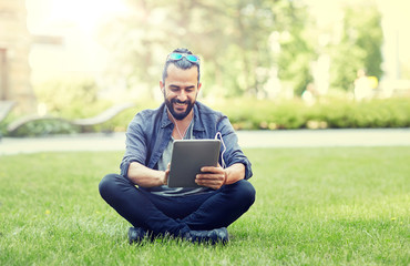 people, music, technology, leisure and lifestyle - happy young hipster man with earphones and...