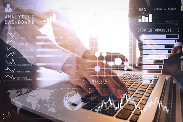 business documents on office table with smart phone and blank screen laptop computer and graph business diagram and two colleagues discussing data in the background