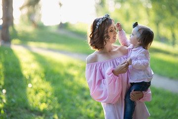 Obraz premium Mom and daughter are two years old sitting on the grass in the park