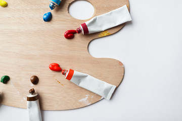 fine art, creativity, painting and artistic tools concept - close up of palette and acrylic color tubes or paint