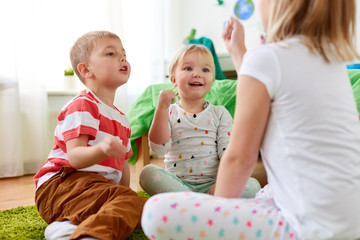 childhood, leisure and family concept - happy little kids playing rock-paper-scissors game at home