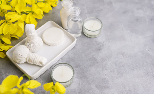 Bright spa background: candles and thai massage herbal bags with bottles and yellow flowers on пкун. Health, skin treatment conceptю Еуче ызфсу