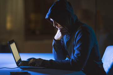 cybercrime, hacking and technology crime - male hacker in dark room using laptop computer for cyber...