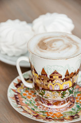 bright cup of cappuccino coffee with marshmallow close-up