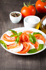Close-up photo of caprese salad with ripe tomatoes, basil, buffalo mozzarella cheese. Italian and Mediterranean food concept. Fresh and healthy organic meal. Starter and antipasti. 