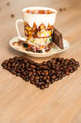 bright cup with coffee beans and sweets on a wooden table