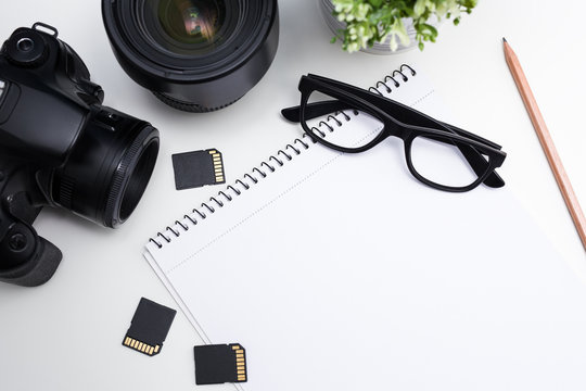 top view of photographer's workplace - camera, photography equipment, notepad and glasses - Powered by Adobe