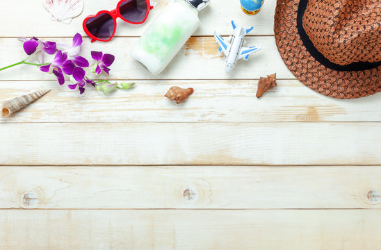 Table top view aerial image of summer & travel beach holiday in the season background concept.Flat lay essentials accessories for travel.White lotion and woman clothing on plank wood and copy space.