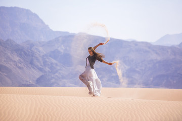 Fototapeta na wymiar Woman standing on a sand dune in the desert of Jordan