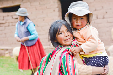 Native american girl with typical aymara cloth holding her little sister outside. - obrazy, fototapety, plakaty