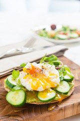 Raw healthy burger with avocado dressing, cucumbers, poached egg and multigrain bread. Superfood snack concept