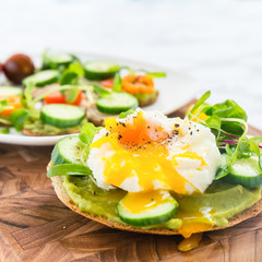 Raw healthy burger with avocado dressing, cucumbers, poached egg and multigrain bread. Superfood snack concept