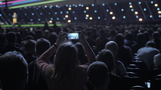 Audience recording video of band on mobile phone in concert.