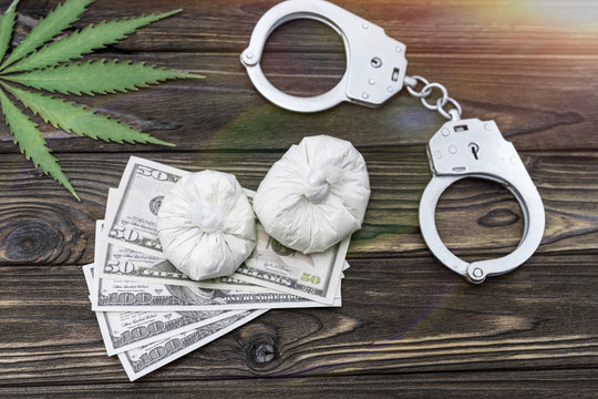 drugs, hemp. dollars, handcuffs on the background of a wooden table