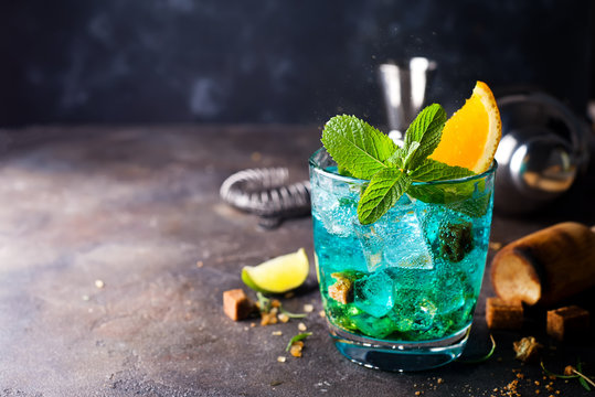 Blue cocktail in glasses with ice, mint and orange