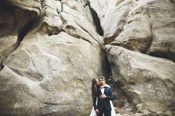 Obraz premium Happy wedding couple kissing and hugging near a high cliff