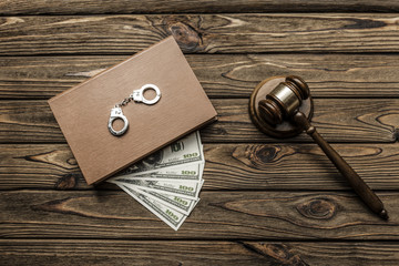 a judge's hammer, a book, American dollar bills, handcuffs on a wooden background. arrest, deposit.