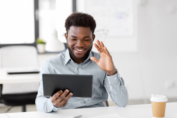 business, technology and communication concept - happy smiling african american businessman having video chat on tablet pc computer at office