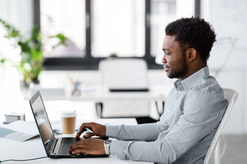 business, people and technology concept - african american businessman with laptop computer working...