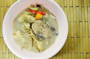 spicy boiled catfish with bamboo shoot and eggplant topping slice finger root in coconut milk soup on bowl
