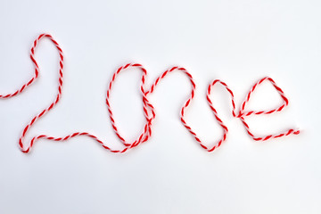 Word love from thread on white background. Inscription love from red and white woolen thread. Valentines Day and love concept.