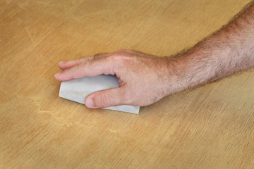 Worker sanding wooden plank, closeup of hand