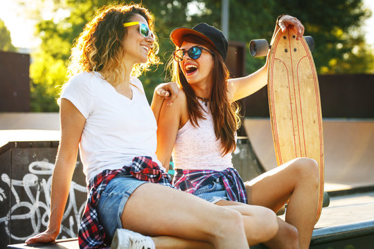 Two female skaters best friends hangout at the skate park on sunset .Laughing and fun.