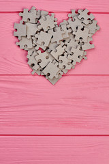 Valentines Day wooden background. Shape of heart from cardboard puzzles on pink wooden table with copy space, top view.