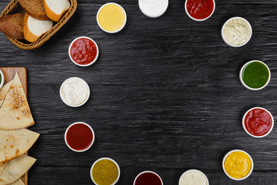 Assorted sauces on a black wooden background with copy space