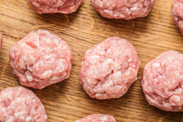 Raw meatballs on the wooden cutting board.