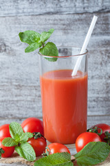 Close-up of a glass of tomato juice with vegetables on wooden sacking background. Vitamins and minerals. Healthy drink concept.