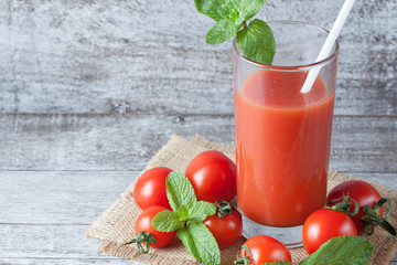 Close-up of a glass of tomato juice with vegetables on wooden sacking background. Vitamins and...