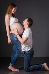 Husband and pregnant wife on gray background
