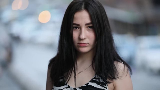 Portrait of shy smiling teenage girl in city, slowmotion