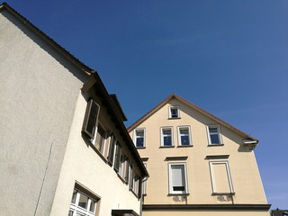 Sanierte Fassaden in Beige und Naturfarben vor blauem Himmel im Sonnenschein in der Hautstraße in...