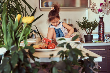 Sweet little cute girl learns to cook a meal in the kitchen.