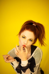 Beautiful young woman in red and yellow fashion portrait with perfect make up enjoying candy, eating