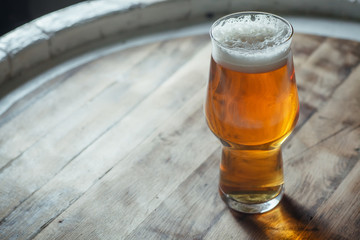 Glass of light beer on a wooden barrel