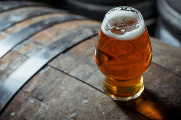 Glass of light beer on a wooden barrel