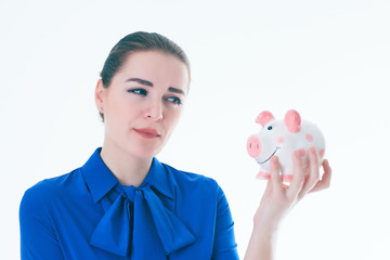 Beautiful Caucasian brunette woman listens to the sound of coinsin a piggybank and dreams.