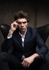 Business portrait of a serious young man sitting in a chair.