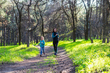 Morning jogging, mom and daughter are running along the forest trail, free space.