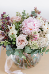 Wedding bouquet of white lilac, roses, peony and buttercup on a wooden table. Lots of greenery, modern asymmetrical disheveled bridal bunch. Spring flowers