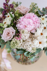 Wedding bouquet of white lilac, roses, peony and buttercup on a wooden table. Lots of greenery, modern asymmetrical disheveled bridal bunch. Spring flowers