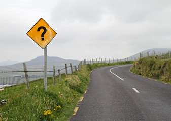 A yellow road sign with a question mark